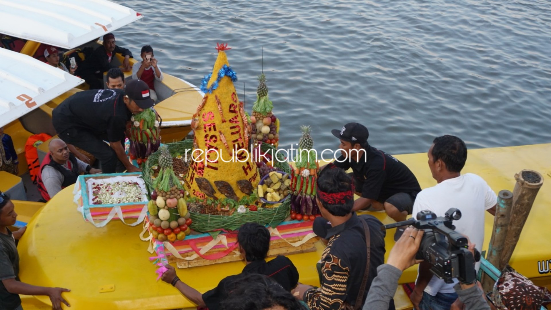LARUNG - Ratusan warga Dusun Telocor, Desa Kedungpandan, Kecamatan Jabon, Sidoarjo bersedekah bumi dengan melarung tumpeng di Dermaga Telocor, Jumat (27/09/2019) petang.