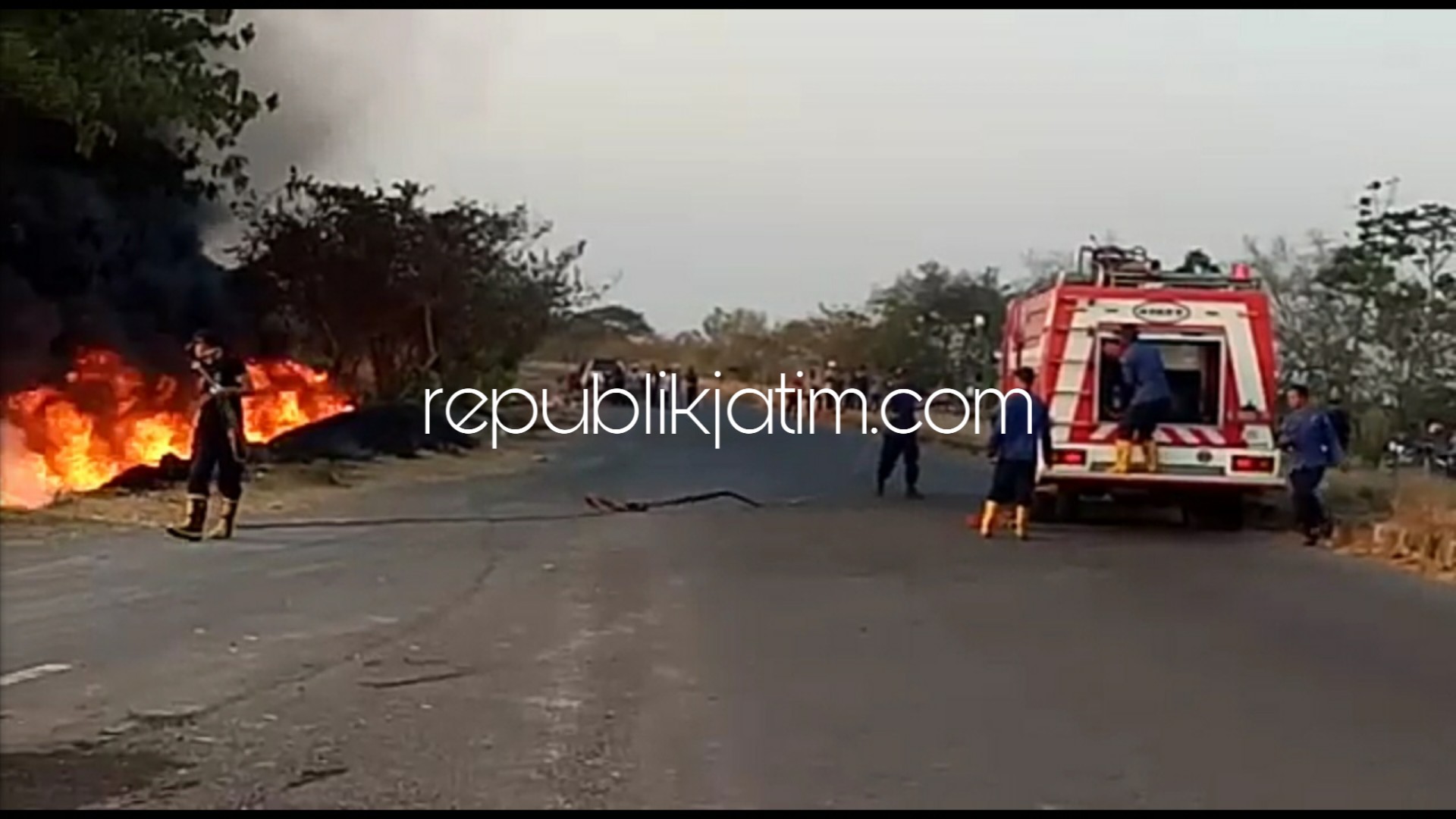 PADAMKAN API - Sejumlah petugas PMK berusaha memadamkan kobaran api dan pembasahan rumput ilalang di JL Raya Exit Tol Lama Desa Besuki, Kecamatan Jabon, Sidoarjo, Kamis (18/10/2018) petang.