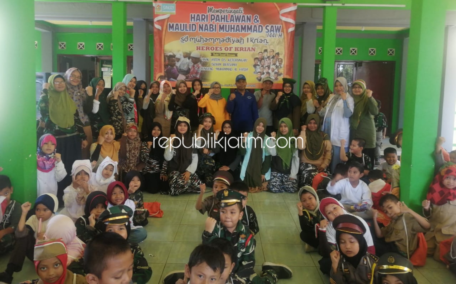 BERSAMA - Ratusan siswa dan siswi kelas 1, 2 dan 3 SD Muhammadiyah 1 Krian berfoto bersama guru dan para perangkat Desa Katerungan, Kecamatan Krian, Sidoarjo saat peringatan Hari Pahlawan dan pemberian santunan, Jumat (08/11/2019).