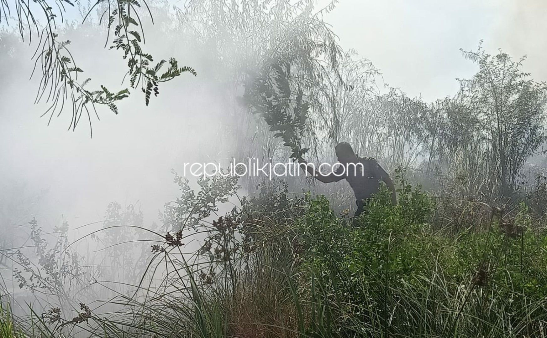 PADAMKAN - Petugas PMK Sidoarjo dan Polsek Tanggulangin berupaya proses pemadaman lahan kosong yang terbakar, Senin (18/11/2019). 