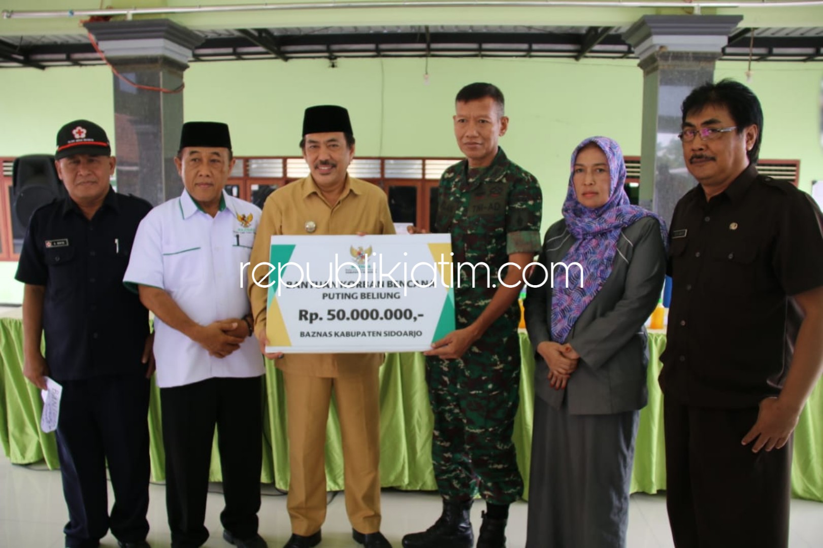 BERIKAN BANTUAN - Wabup Sidoarjo, Nur Ahmad Syaifuddin menyerahkan bantuan uang tunai Rp 50 juta dan semen 160 sak kepada Kepala Posko Bencana Puting Beliung, Kapten Parlan di Balai Desa Kajeksan, Kecamatan Tulangan, Senin, (26/11/18).