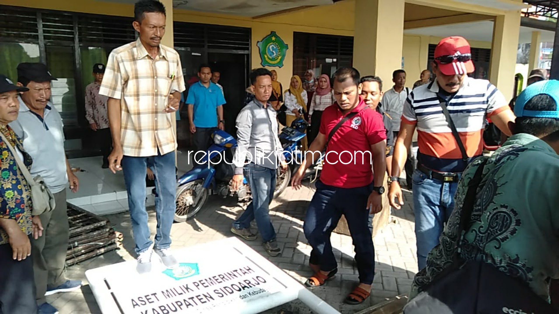DIROBOHKAN - Sejumlah warga mencabut dan merobohkan papan bertuliskan Aset Pemerintah Kabupaten Sidoarjo yang dipasang di UPTD Krembung, Sidoarjo, Senin (02/12/2019) kemarin. 