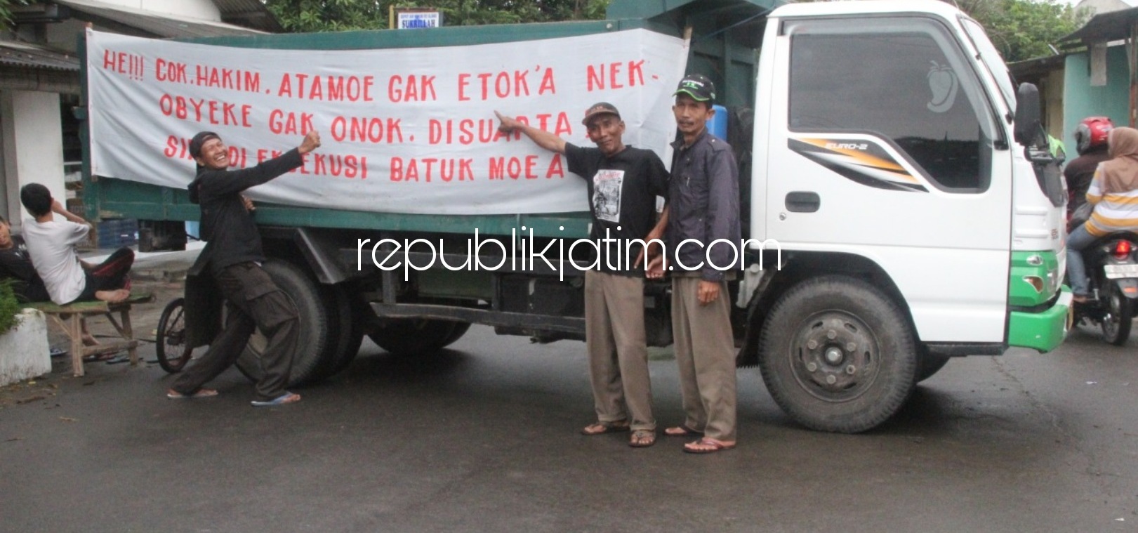 BLOKADE JALAN - Warga Desa Kemiri, Kecamatan/Kabupaten Sidoarjo memblokade jalan menggunakan truk dan memasang spanduk penolakan rencana penyitaan aset desa mereka, Selasa (15/12/2020). 