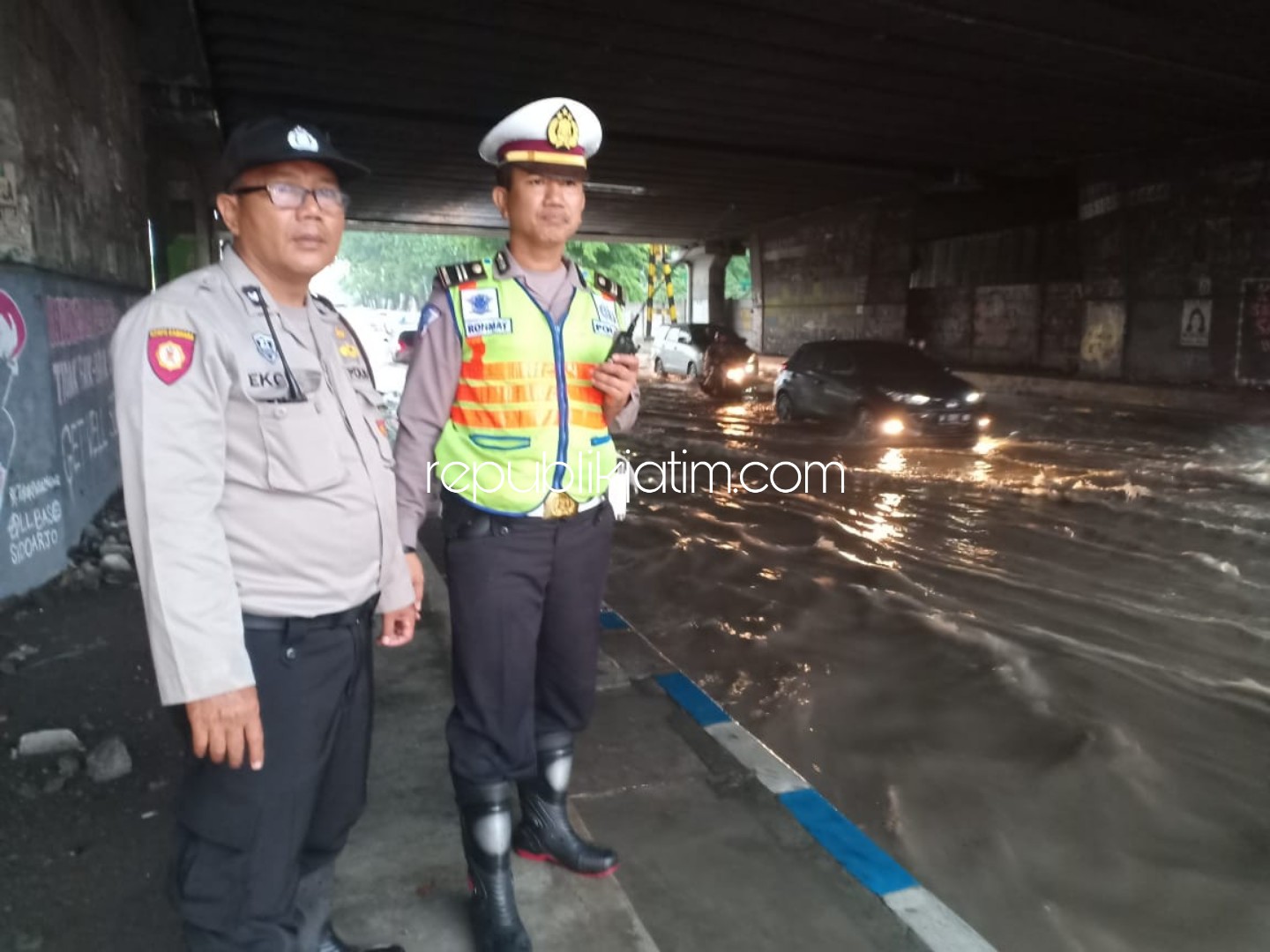 TERJUN - Kanit Patroli Turjawali, Satuan Lantas, Polresta Sidoarjo, Iptu Rohmat dan sejumlah anggota Lantas sibuk membantu para pengguna jalan yang terjebak banjir dan mengatur arus lalu lintas di bawa Tol Jati, Kecamatan Sidoarjo, Rabu (25/12/2019).