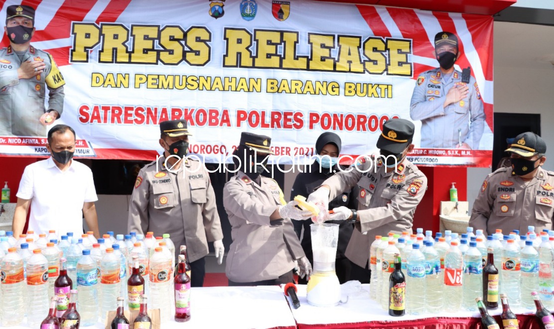 MUSNAHKAN - Wakapolres Ponorogo Kompol Meiridiani memimpin pemusnahan ratusan liter miras dan ribuan pil Doubel L dihalaman Polres Ponorogo, Senin (27/12/2021).