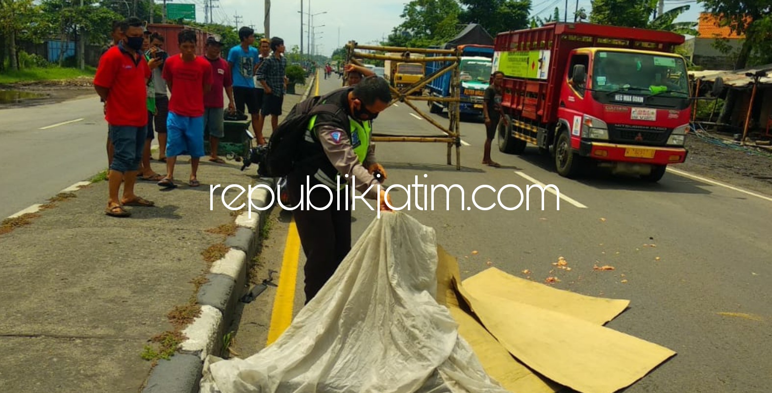 TEWAS - Petugas dan warga mengevakuasi korban kecelakaan Arif (34) warga Nganjuk yang tewas saat berusaha mendahului truk fuso di JL Raya Bypass Krian tepatnya depan PT Haka Krian, Sidoarjo, Senin (28/12/2020).