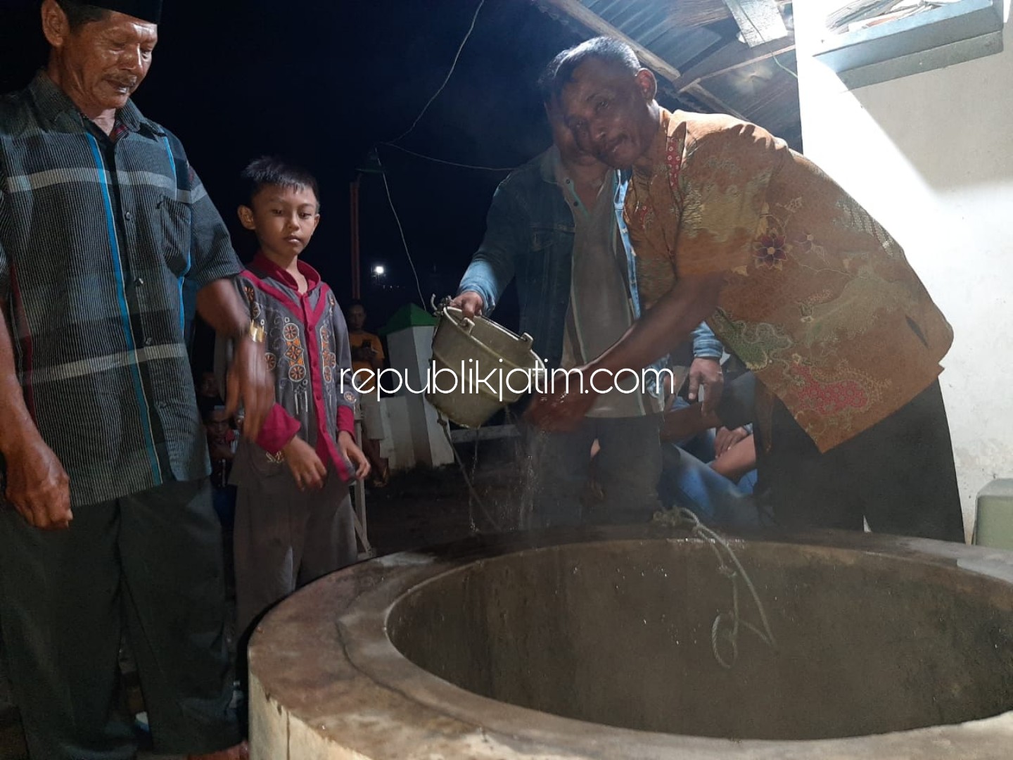 PANAS - Sejumlah warga Desa Watutulis, Kecamatan Prambon, Sidoarjo mendatangi sumur yang ada di makam desa setempat untuk merasakan panas air sumur yang mencapai 42 derajar selsius, Sabtu (28/12/2019) malam.