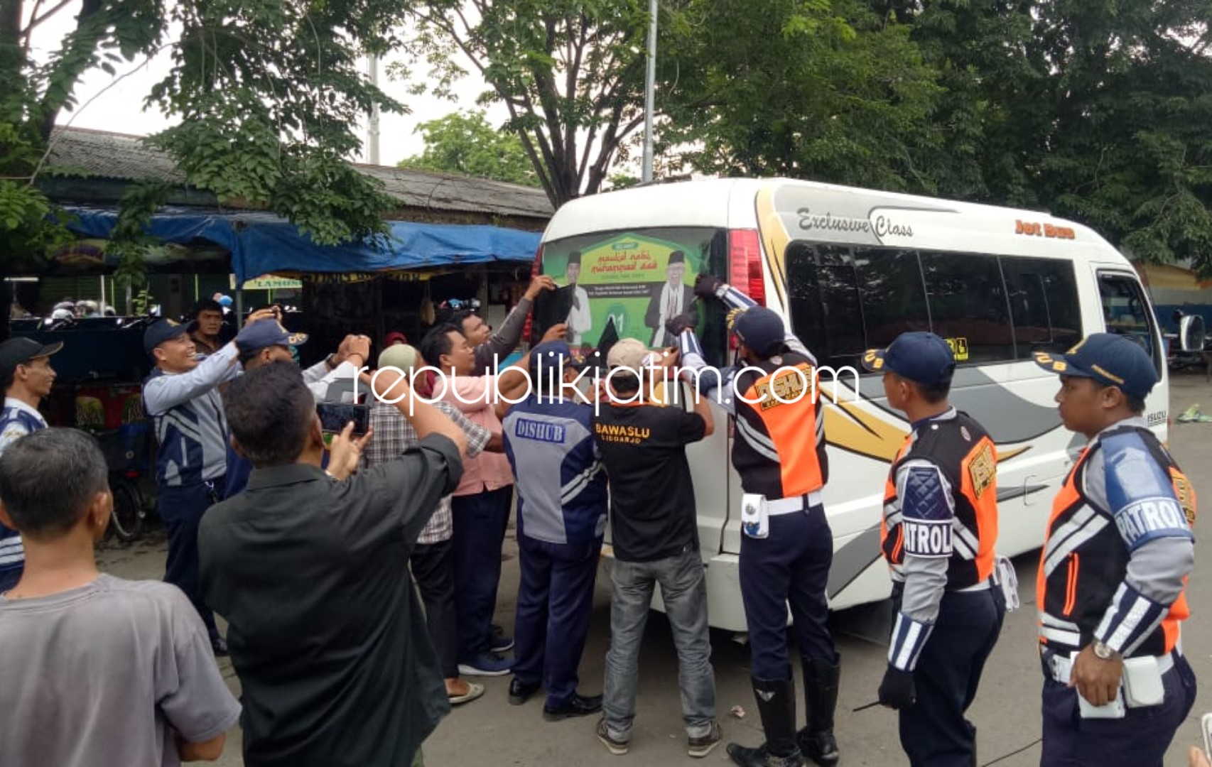 PENERTIBAN - Bawaslu dibantu petugas gabungan menertibkan angkutan yang dibranding pemasangan calon Presiden dan Wakil Presiden dengan cara dicopot di Terminal Pasar Larangan, Candi, Sidoarjo, Jumat (28/12/2018) sore.