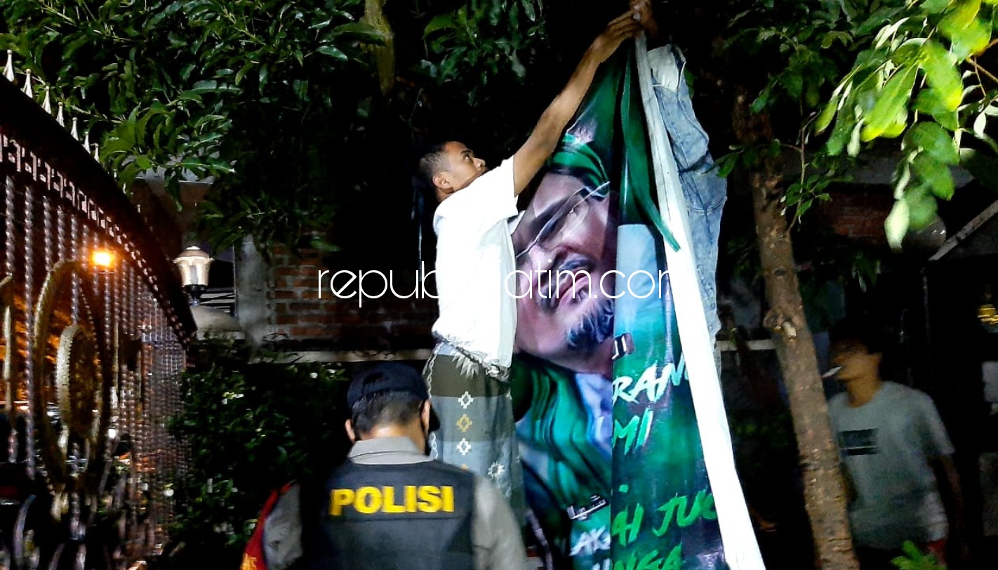 DITURUNKAN - Spanduk Habib Rizieq Shihab (HRS) di pekarangan warga Mojosantren, Kemasan, Kecamatan Krian, Sidoarjo diturunkan atas perintah Kapolresta Sidoarjo Kombes Pol Sumardji dan Kapolsek Krian AKP Mukhlason, Rabu (30/12/2020) malam.
