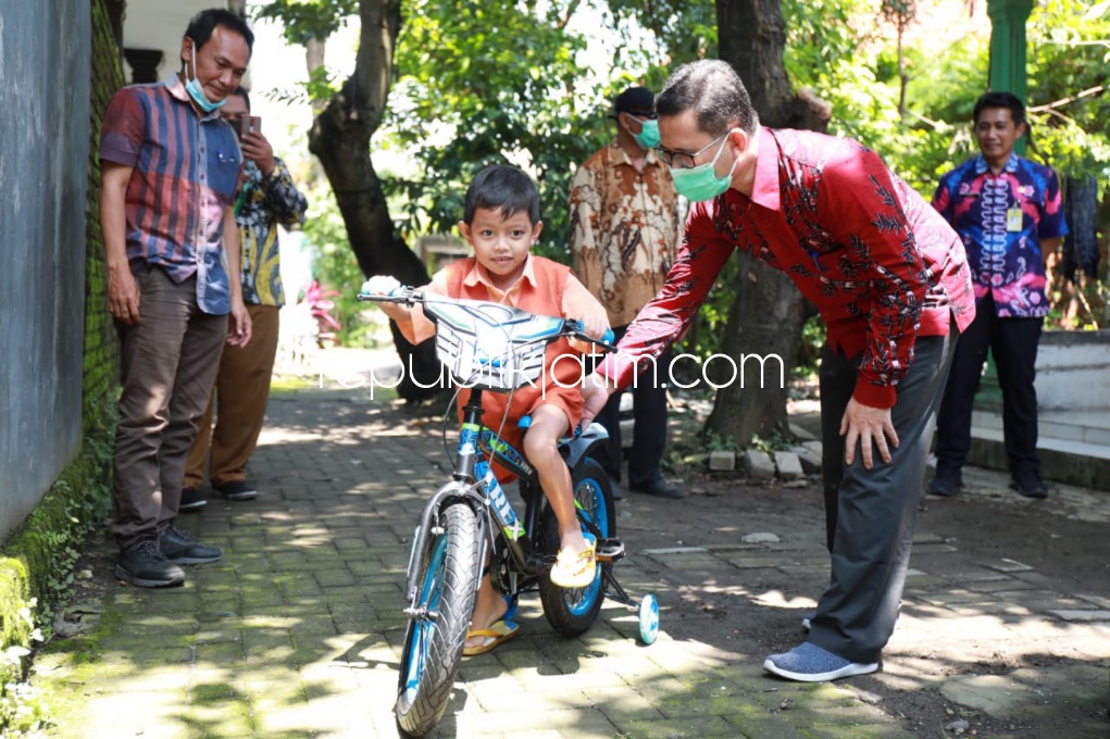BAHAGIA - Wajah ceria dan bahagia nampak dari Achmad Rizal Kurdianto bocah yang masuk daftar pasien tunggu operasi di RS dr Soetomo Surabaya saat menerima sepeda dari Bupati Sidoarjo, Ahmad Muhdlor Ali, Selasa (22/02/2022).