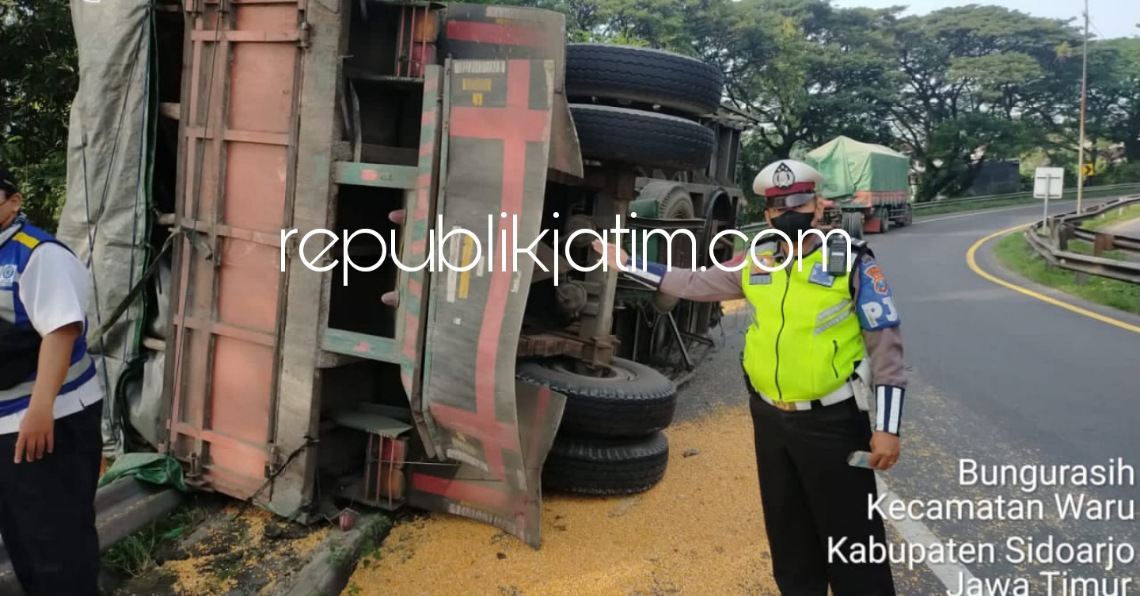 TERGULING - Sebuah truk gandeng pengangkut jagung terguling di Exit Tol Waru arah Medaeng masuk Desa Bungurasih, Kecamatan Waru, Sidoarjo, Rabu (23/03/2022). 