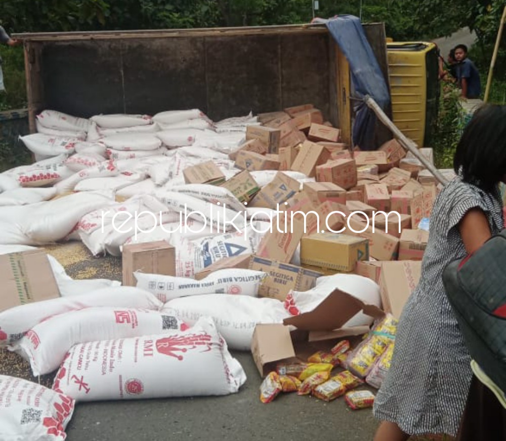 TERGULING - Sejumlah polisi dan warga ikut mengevakuasi truk pengangkut sembako yang terguling di tanjakan Dusun Gunung Thukul, Desa Suru, Kecamatan Sooko, Ponorogo, Sabtu (16/04/2022). 