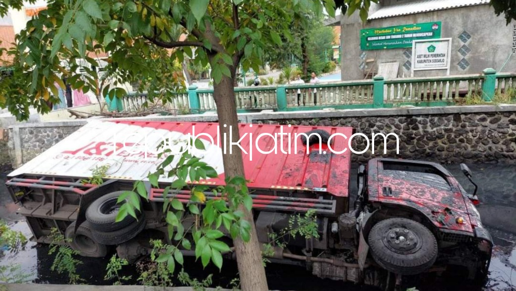 TERGULING - Sebuah truk box ekspedisi bernopol L 9646 CJ yang dikemudikan Muhamad Ainun Hardiyanto (40) warga Simo Kwagean Buntu, Kota Surabaya terbalik di Sungai Depan SDN Trosobo 2 Kecamatan Taman, Sidoarjo, Sabtu (16/04/2022) sore.