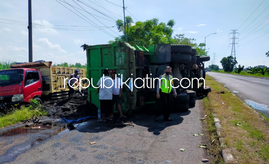 TERGULING - Sebuah dump truk bernopol N 8570 UR yang dikendarai Bunadi (54) warga Dusun/Desa Lempeni, Kecamatan Tempeh, Kabupaten Lumajang terguling di JL Raya Arteri Porong, Sidoarjo, Minggu (12/06/2022).