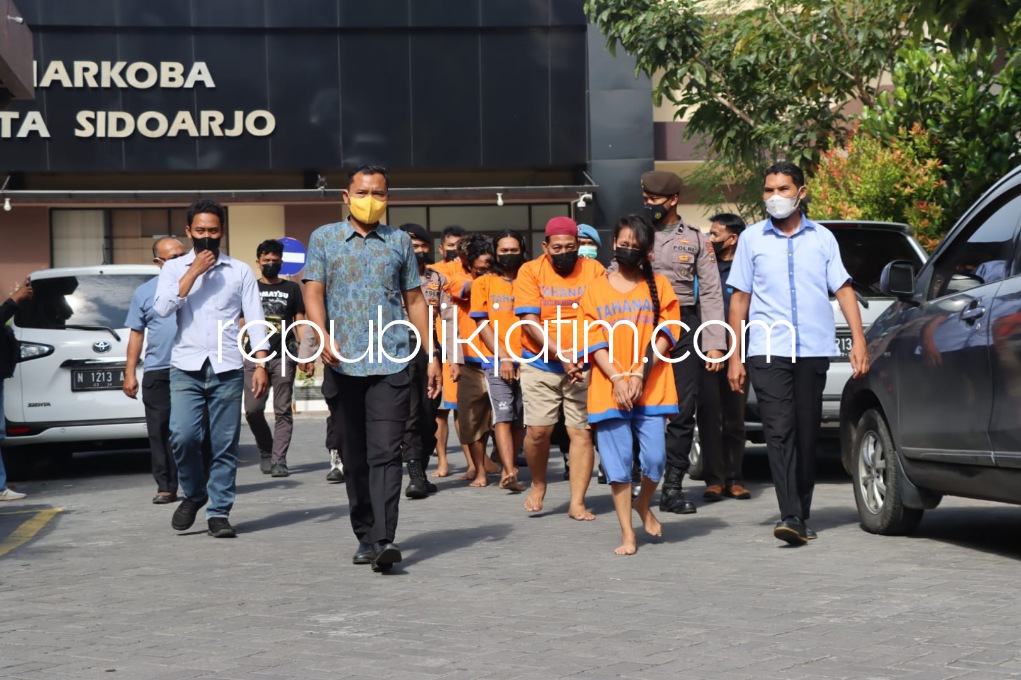 GELANDANG - Para tersangka hasil penggerebekan kamar kos di wilayah Kecamatan Taman, Sidoarjo digelandang petugas Satuan Resnarkoba, Polresta Sidoarjo beserta barang buktinya, Rabu (13/07/2022).