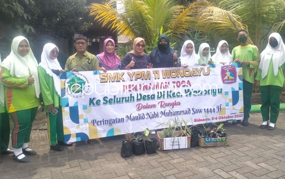 TANAMKAN - Kepala SMK YPM 11 Wonoayu, Siti Masru' ah menanamkan azas manfaat bagi sesama kepada para siswa saat pengajuan dan shalawatan serta Kades Tanggul, Syaiful Akhmadi menerima tanaman Toga dari SMK YPM 11 Wonoayu, Jumat (07/10/2022).