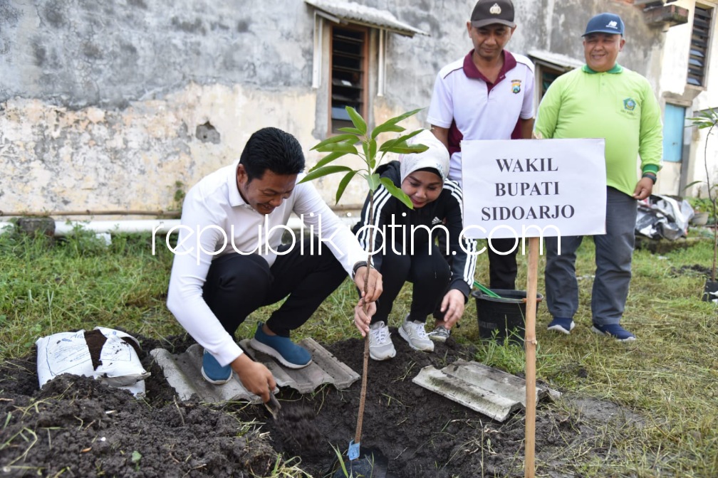 TANAM - Wabup Sidoarjo, Subandi ditemani istrinya dr Sriatun Subandi menanam pohon mangga di lahan TKD Desa Pabean, Kecamatan Sedati, Sidoarjo, Sabtu (21/01/2023). 