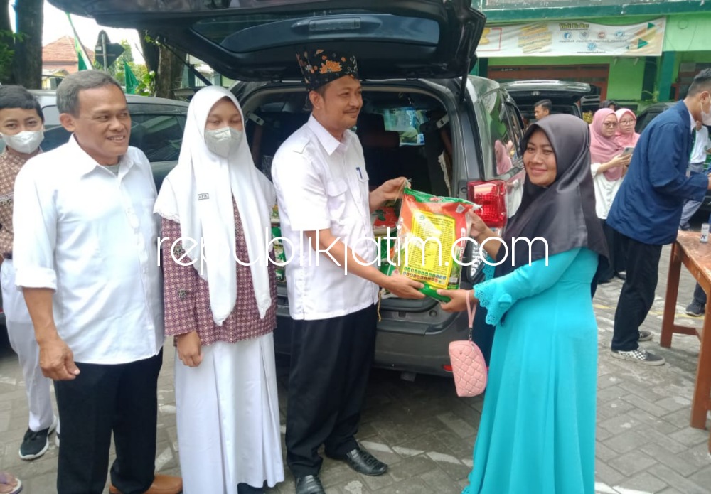SERAHKAN - Kepala SMP YPM 6 Tarik, Nanang Wahyono secara simbolis menyerahkan sembako kepada pembeli pasar murah saat acara Gebyar Pasar Murah dan Pengobatan Gratis, Rabu (01/02/2023).
