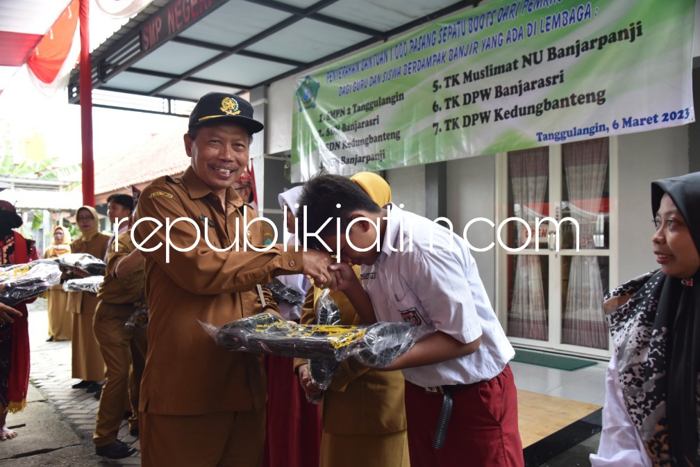 BANTUAN - Kepala Dinas Pendidikan dan Kebudayaan Pemkab Sidoarjo, Dr Tirto Adi menyerahkan 1.000 pasang sepatu boots untuk guru dan siswa yang sekolahnya terdampak banjir di SMPN 2 Tanggulangin, Senin (06/03/2023). 
