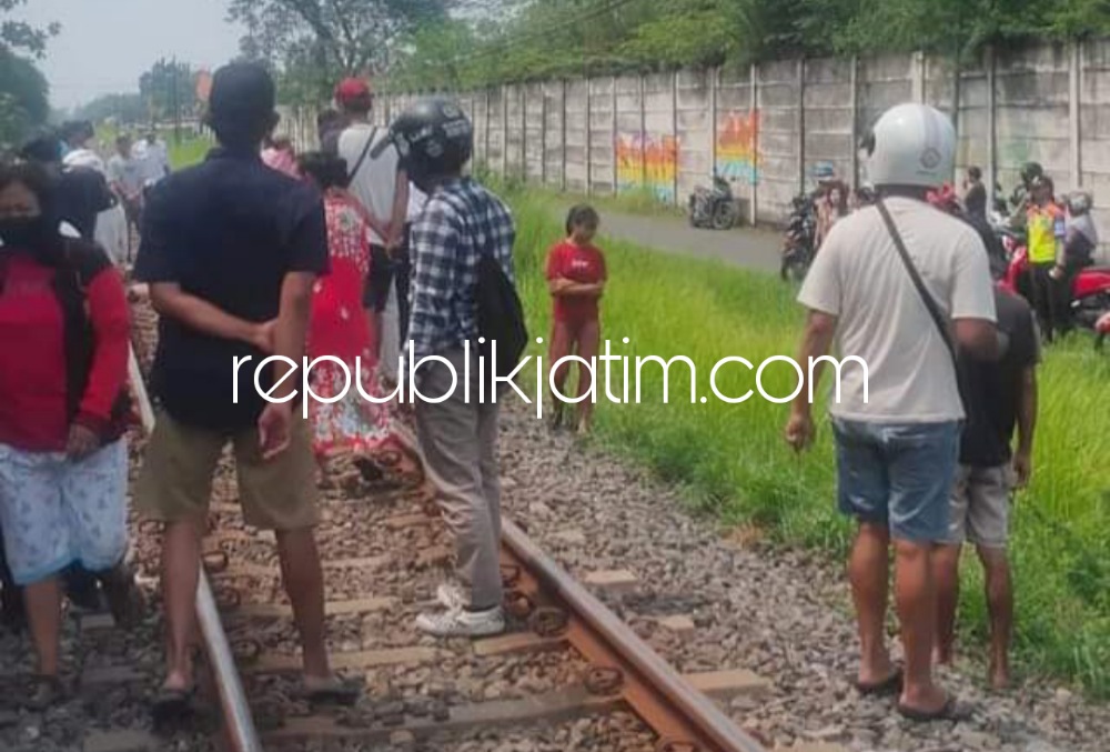 EVAKUASI - Sejumlah warga dan petugas mengevakuasi korban tertabrak Komuter di perlintasan KA Desa/Kecamatan Candi, Sidoarjo, M Tri Ardiyanto (26) warga Desa Sugihwaras, Kecamatan Candi, Sidoarjo, Jumat (24/03/2023).