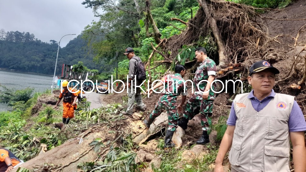 TUTUP - Sejumlah anggota Koramil Ngebel bersama BPBD ikut kerja bakti membersihkan puing longsor yang menutup Jalan Lingkar Telaga Ngebel, Kecamatan Ngebel, Ponorogo, Senin (27/03/2023).