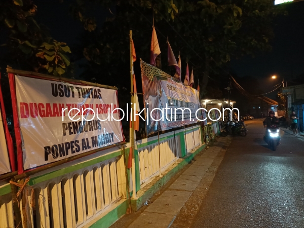 TUNTUTAN - Warga Desa Pagerwojo, Kecamatan Buduran, Sidoarjo memasang puluhan spanduk dan banner di depan Ponpes Al Mahdiy yang ada di barat Makam Aulia Mbah Ud untuk segera ditutup, Kamis (20/06/2024) malam.