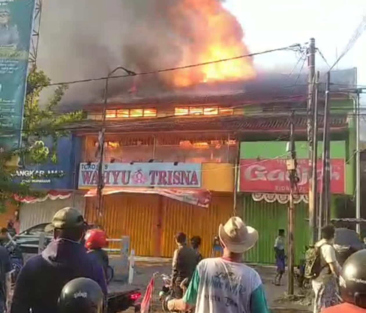 PADAMKAN - Sejumlah petugas PMK dan pedagang berupaya memadamkan api yang melalap ratusan kios dan stan yang ada di Pasar Krian, Sidoarjo, Selasa (20/08/2024). 