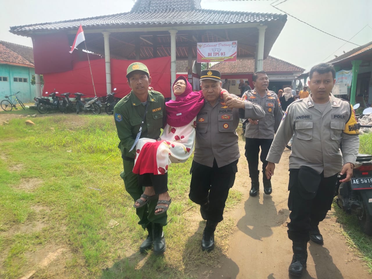 Petugas Polsek Kwadungan bersama Linmas mengevakuasi seorang nenek yang pingsan ke puskesmas terdekat saat antri mencoblos di TPS 03 Desa Kwadungan