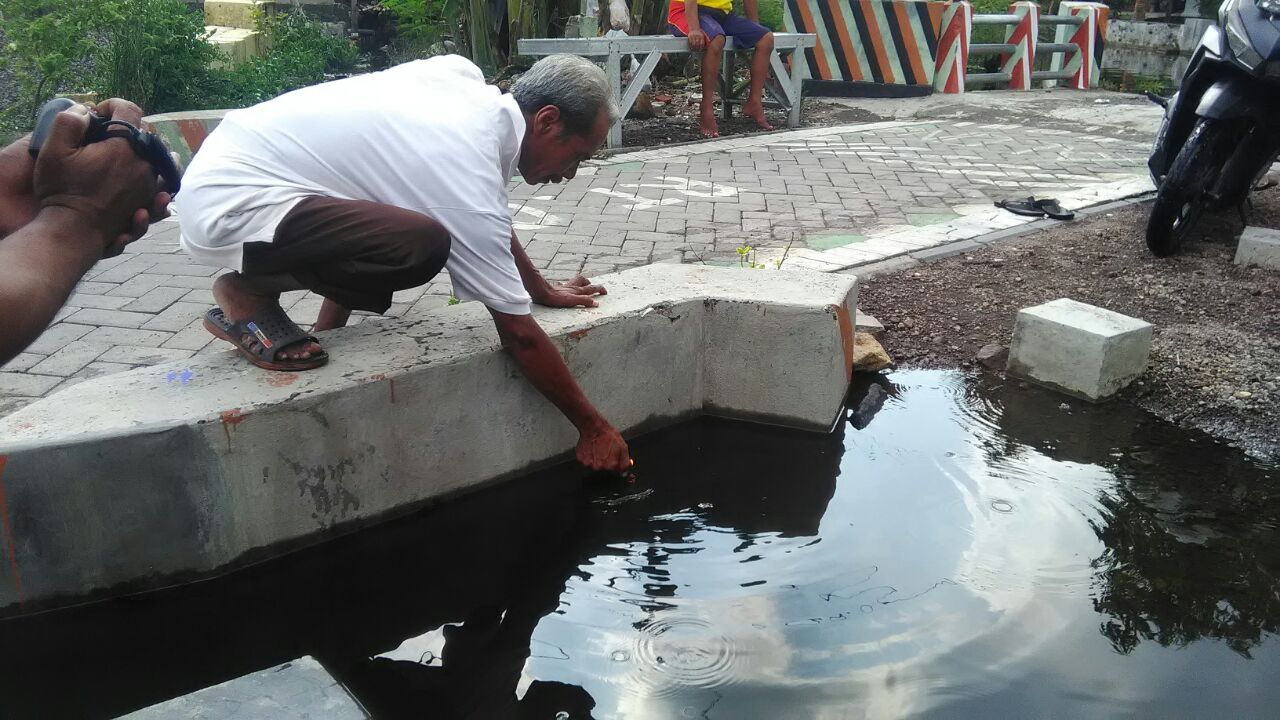 GELEMBUNG GAS - Salah seorang warga Desa Candipari, Kecamatan Porong mrncoba bubble gas (gelembung gas) yang keluar menggunakan korek api. Hasilnya gelembung-gelembung gas itu menyalah, Minggu (26/11/2017).