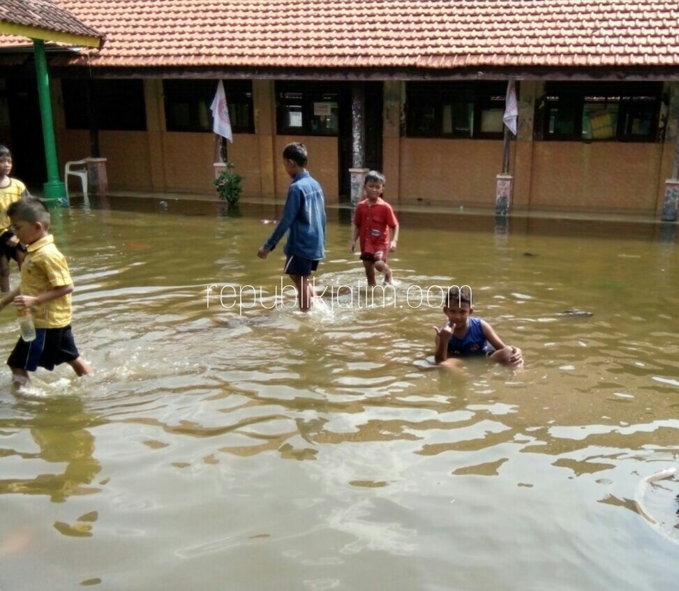 BANJIR - Para siswa SDN Kupang, Kecamatan Jabon, Kabupaten Sidoarjo terpaksa mengikuti Ujian Akhir Semester (UAS) dengan nyeker karena rumah dan sekolah mereke terendam banjir, Kamis (07/12/2017).